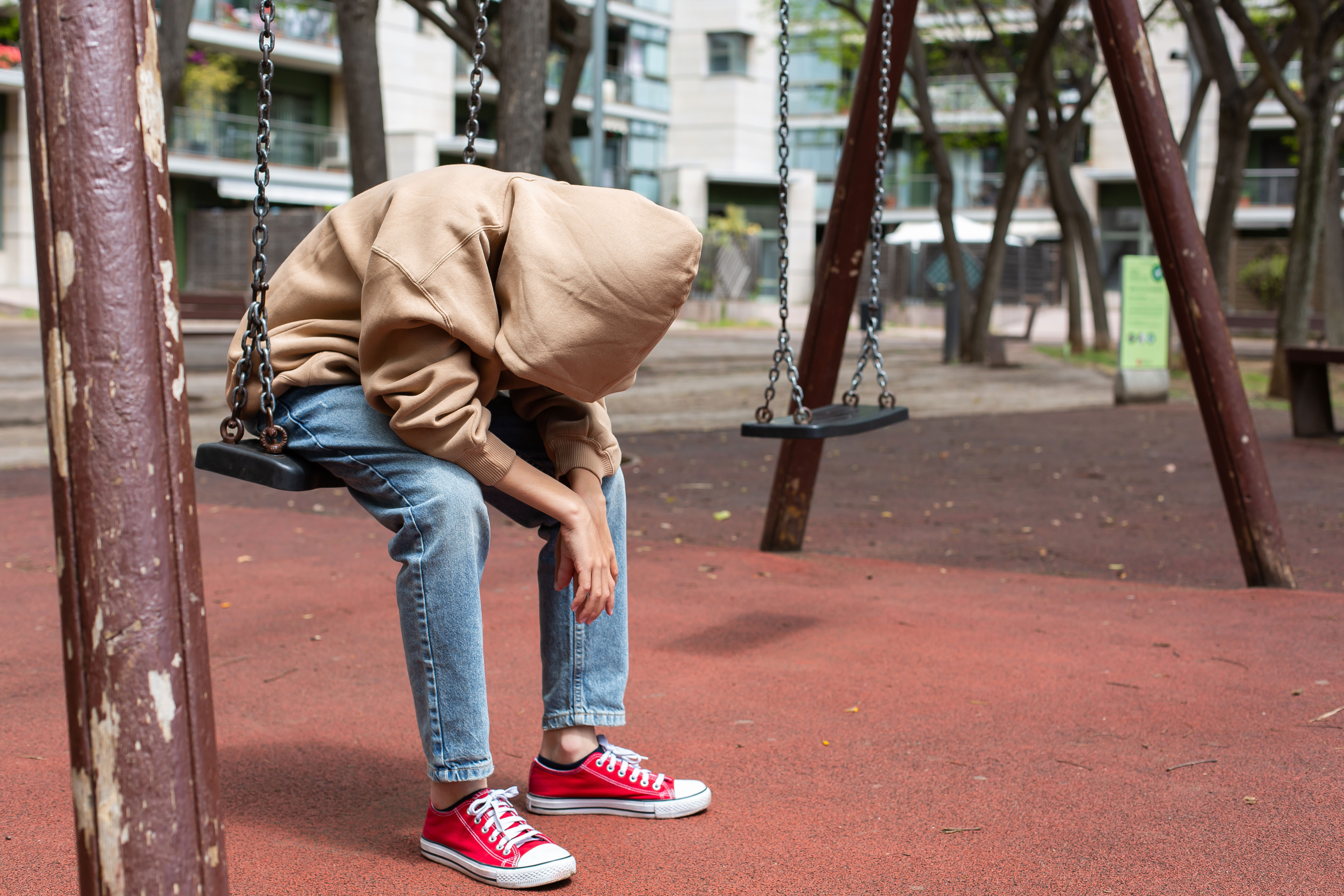 A teen sitting on a bench leaning over