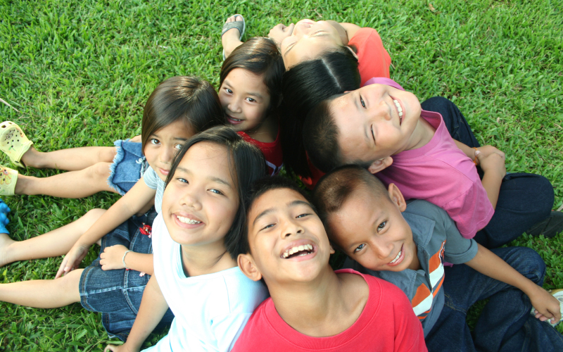 Students sitting with their backs to each other, smiling while looking at the camera