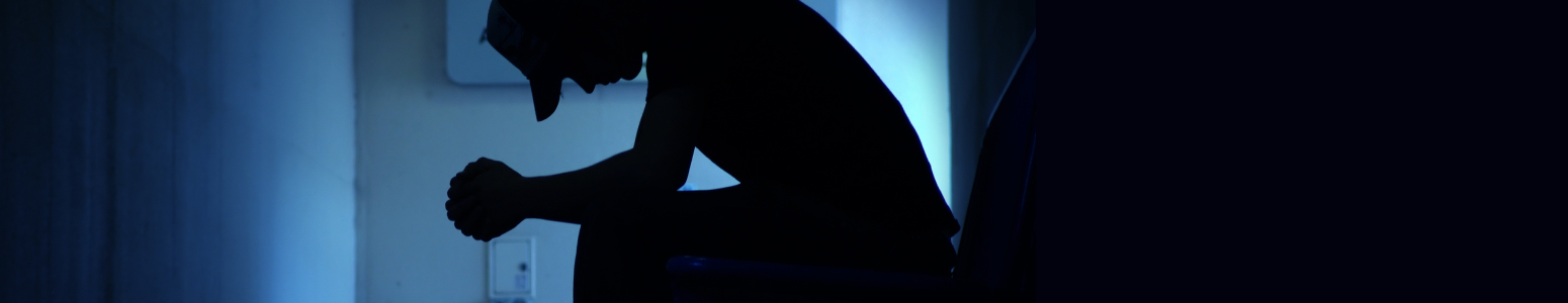 Student sitting with hands clasped, looking down and dejected