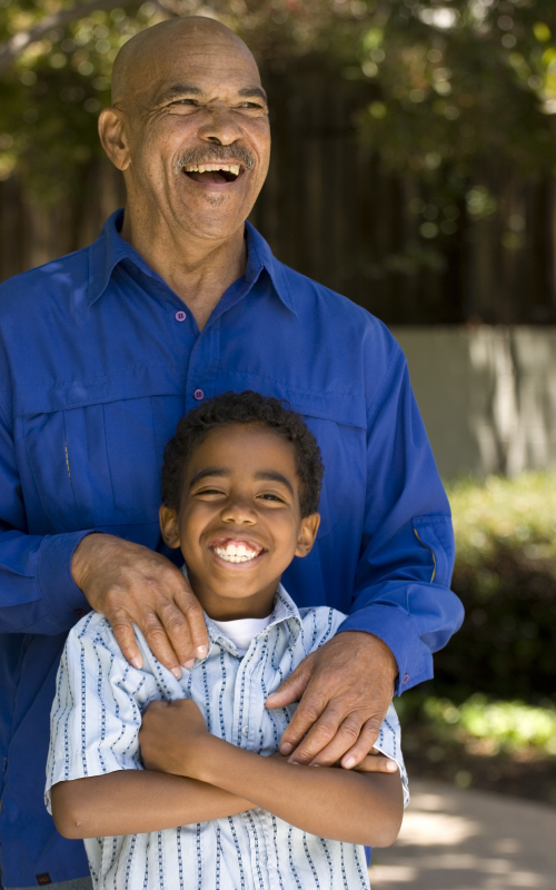 Father and son laughing together, with the father's hands on the son's shoulders