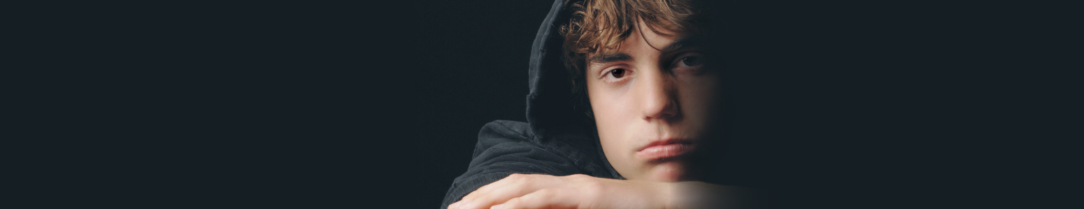 High school male student in a black hoodie, with a black background